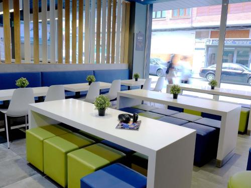a room with tables and chairs with a cat on a book at ibis budget Bilbao City in Bilbao