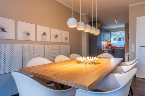 a dining room with a wooden table and white chairs at Haus Tidehuus in Borkum
