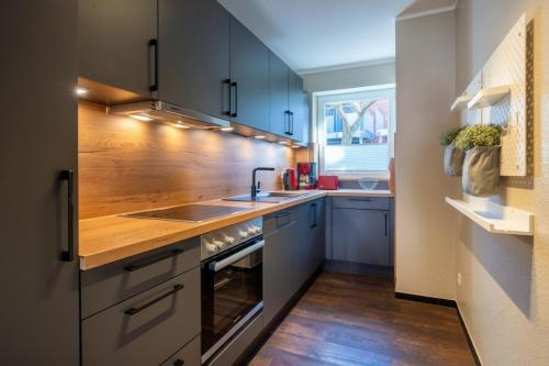 a kitchen with blue cabinets and a sink and a window at Haus Tidehuus in Borkum
