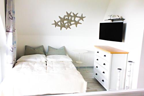 a bedroom with a white bed and a tv at Seestern in Neuenkirchen auf Rugen