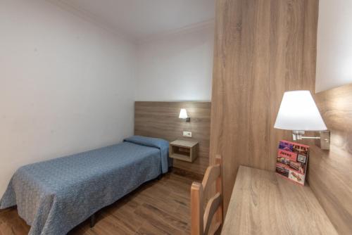 a small room with a bed and a table at Pensión San Andrés I in Jerez de la Frontera