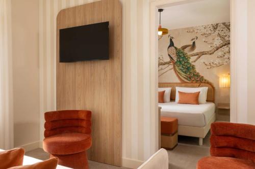 a hotel room with a bed and a tv on a wall at Hotel La Tonkine ex Olympia in Beausoleil