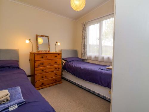 a bedroom with two beds and a dresser and a window at Sea Breeze in Bideford