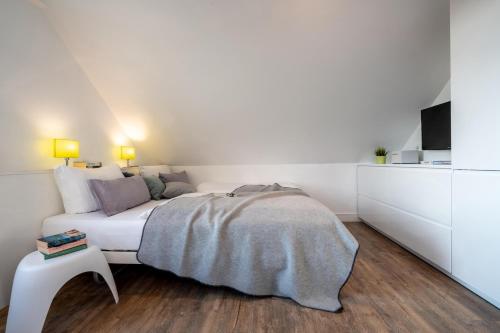 a white bedroom with a bed and a table at Haus Nordstern Wohnung 5 in Borkum