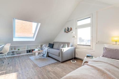 a bedroom with a couch and a chair and a window at Haus Nordstern Wohnung 5 in Borkum