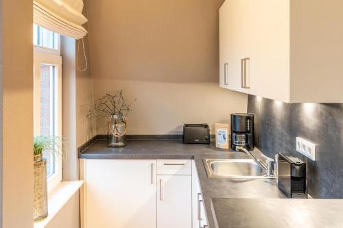 a kitchen with white cabinets and a sink at Logierhaus K15 Appartement 10 in Borkum