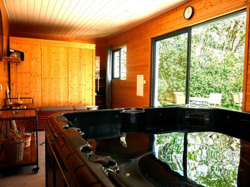 a bath tub in a room with a large window at Clos De La Gourmandière, Maison d'hôtes & Restaurant in Saint-Lothain