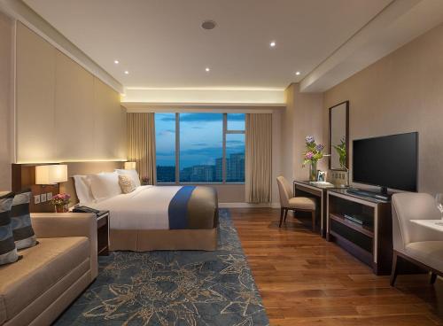 a hotel room with a bed and a television at Ascott Bonifacio Global City Manila in Manila