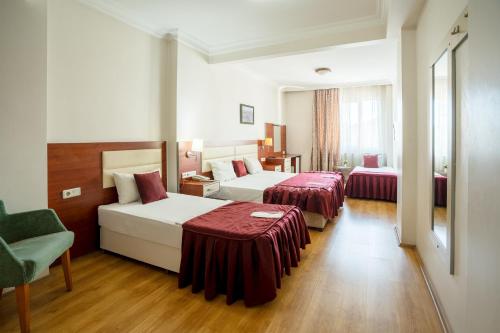 a hotel room with two beds and a chair at La Garden Hotel Old City in Istanbul