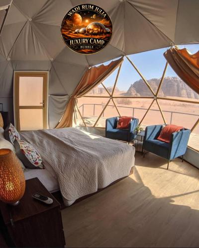 a bedroom in a tent with a bed and two chairs at WADI RUM JULIA lUXURY CAMP in Wadi Rum