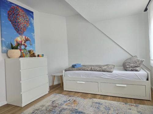 a white bedroom with a bed and a dresser at Ferienwohnung Rückerts Gartenblick in Nordhausen