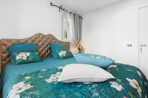 a bed with two blue pillows on top of it at Maison avec piscine Soleil d'Azur in Fréjus