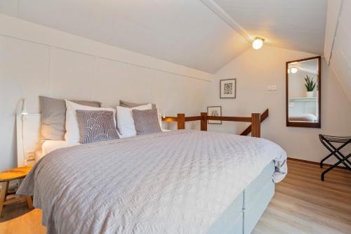 a bedroom with a large white bed and a mirror at Huisje De Koning in Zandvoort