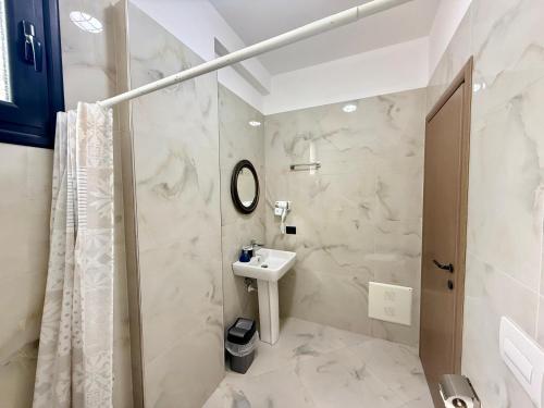 a white bathroom with a sink and a mirror at Actium in Vlorë
