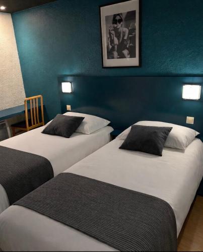 dwa łóżka w pokoju z niebieskimi ścianami w obiekcie Hôtel Restaurant le Privilège - authentic by balladins w mieście Verdun