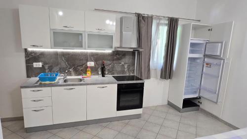 a kitchen with white cabinets and a sink at Apartmani Darijo in Čelina