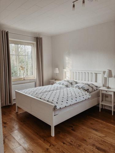 a white bedroom with a large bed and a window at Ankerplatz in Leer