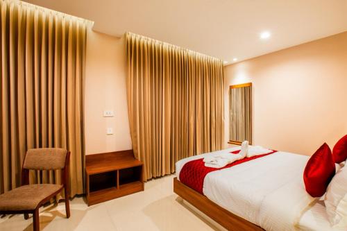 a bedroom with a bed and a desk and a chair at HOTEL GANGa in Mūvattupula