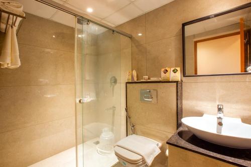 a bathroom with a shower and a sink and a toilet at HOTEL GANGa in Mūvattupula
