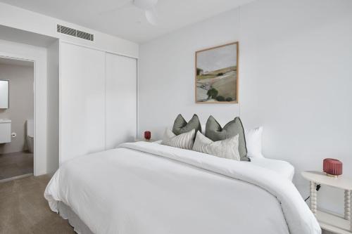 a white bedroom with a white bed with pillows at The Ellery in Newcastle