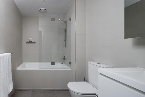 a white bathroom with a toilet and a shower at The Ellery in Newcastle