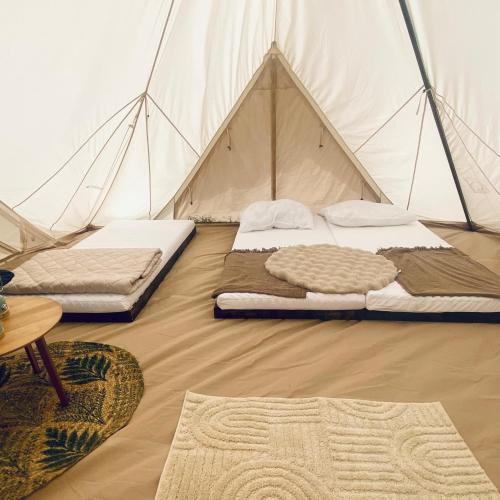 a tent with two beds and a table and a rug at Wiesn-Relax-Camping in Ranten