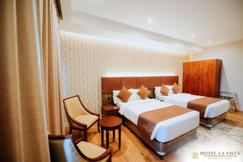 a hotel room with two beds and chairs at Hotel La Vista by Grotto Vista in Mangangpico