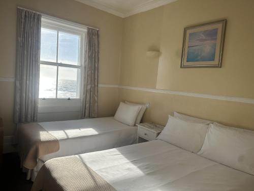 a hotel room with two beds and a window at The Lindum in Hastings