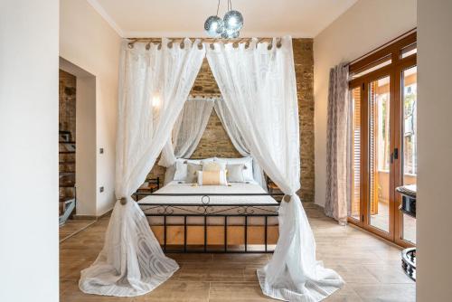 a bedroom with a canopy bed with white drapes at Absinthia Legacy in Soroni