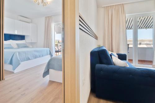 a bedroom with a bed and a blue couch in front of a mirror at Apartments Sonja in Tučepi