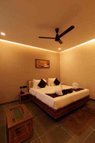 a bedroom with a bed with a ceiling fan at Anasvara Hotels in Mysore