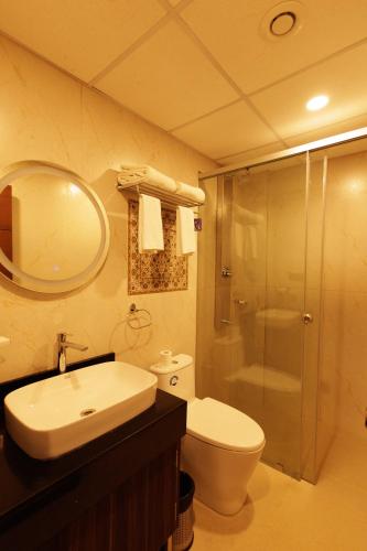 a bathroom with a toilet and a sink and a shower at Anasvara Hotels in Mysore