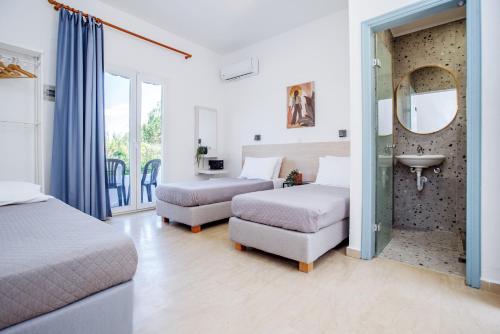 a bedroom with two beds and a sink and a mirror at Seaside Resorts in Kavos