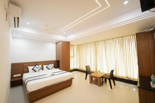 a bedroom with a bed and a table and a window at Sri Sai Lotus In in Bangalore