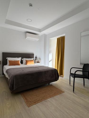 a bedroom with a large bed and a chair at Musical Hostel in Albufeira