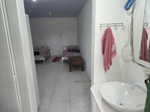 a bathroom with a sink and a room with a couch at Pousada Quintal Verde Floripa in Florianópolis