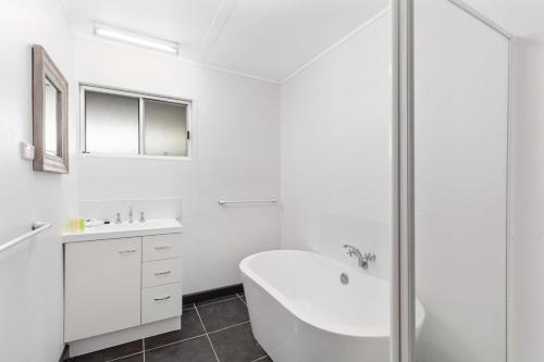 a white bathroom with a tub and a sink at Fennell House in Robe