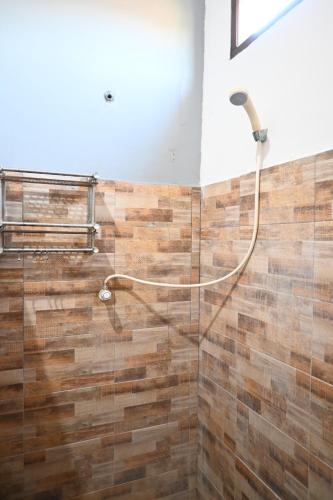 a shower in a bathroom with wooden tiles at Chika House in Gili Trawangan