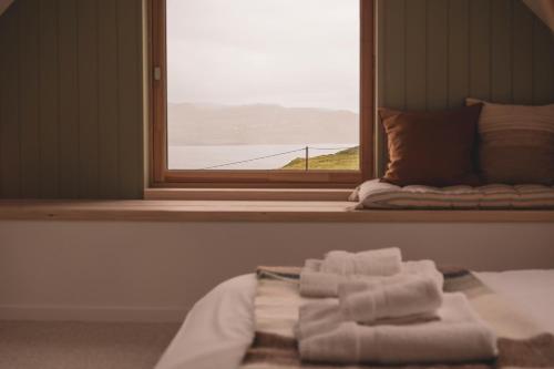 a bed with towels on it in front of a window at Ullinish House in Ullinish