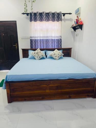 a wooden bed with blue sheets in a bedroom at Blue Heaven in Mannar