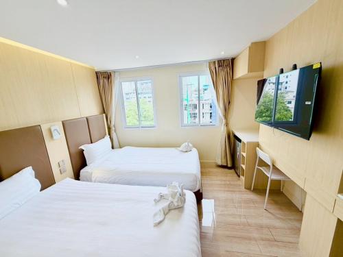 a hotel room with two beds and a flat screen tv at Le Hong Hotel Pratunam in Bangkok