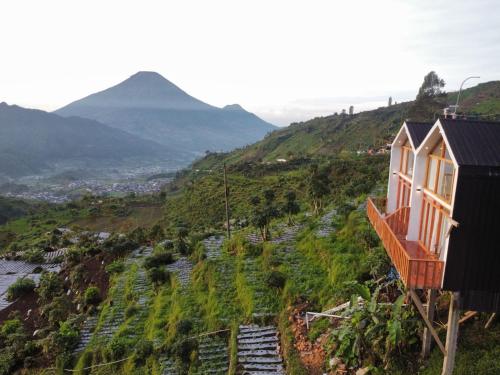 a house on a hill with a mountain in the background at Tribuana villa Dieng in Kejajar