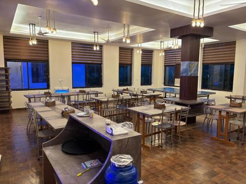 a dining room with tables and chairs and windows at Corbett Treat Resort in Rāmnagar