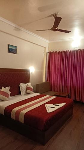 a hotel room with a bed and a red curtain at Hotel sunrise in Kodaikānāl