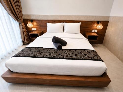 a bedroom with a large bed with a wooden headboard at Jepun Segara Guest House in Kuta