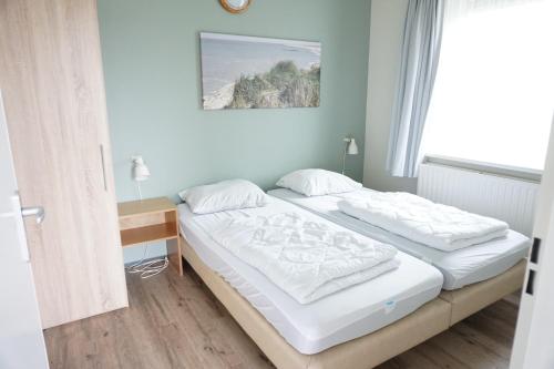 a bedroom with two beds and a window at Kustverhuur, Oude manege Nieuwvliet, Nieuwvliet 1 - 2 in Nieuwvliet