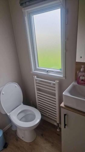 a bathroom with a white toilet and a window at 3 Bed - Sleeps 8 - Family & Pet Friendly in Skegness
