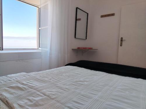 a white bed in a room with a window at Bougainvillea House in Ponta do Pargo
