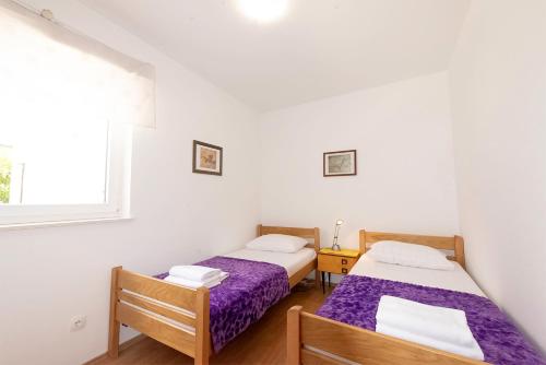 a bedroom with two beds and a window at Apartments Silvia in Novalja