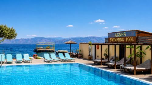 a swimming pool at a hotel with chairs and the water at Agnes Beach Hotel Apartments in Kavos